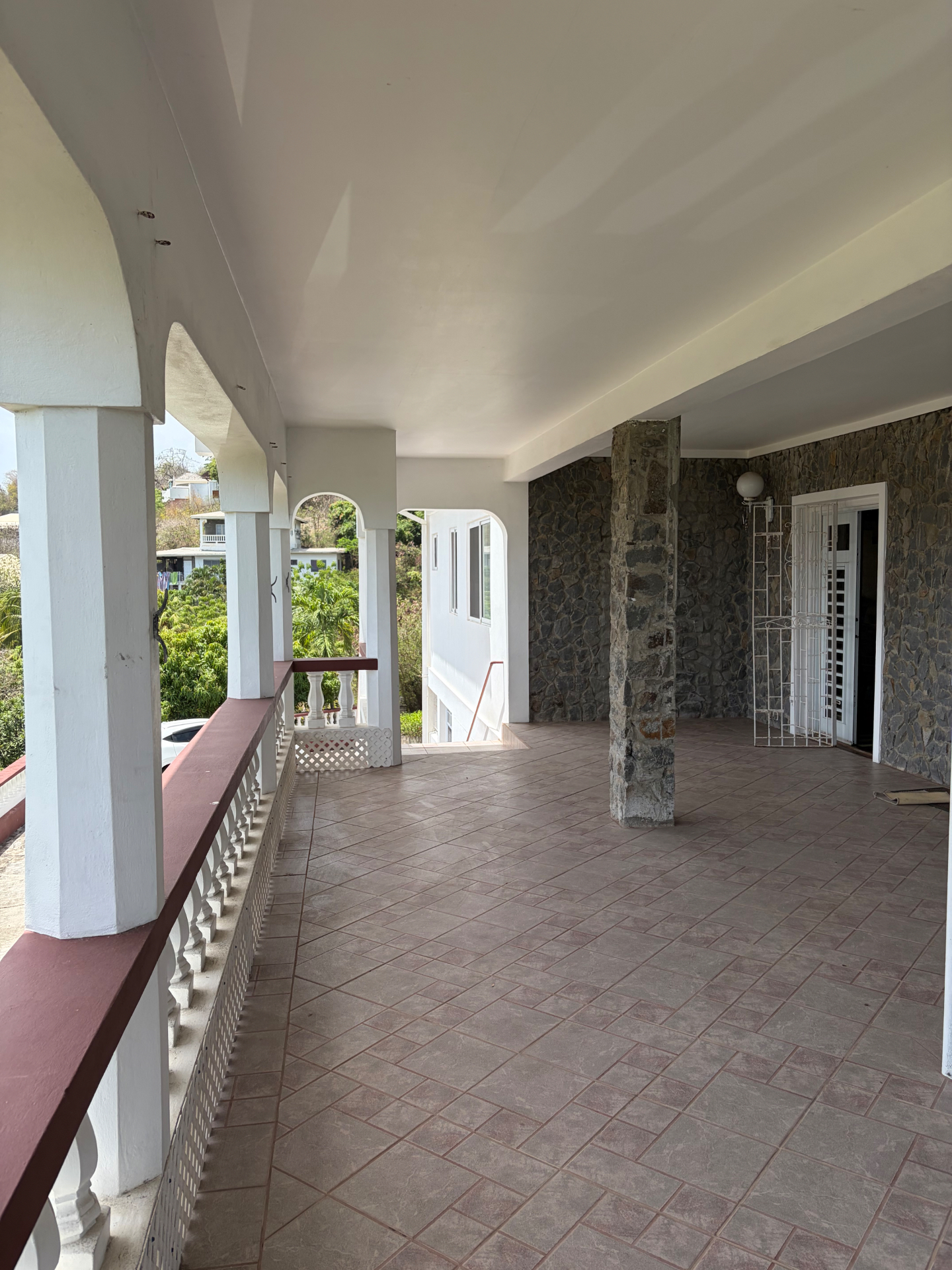 Spacious tiled balcony with arched columns and stone feature wall