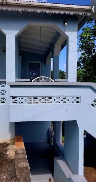 Front view of the blue two-storey home with veranda