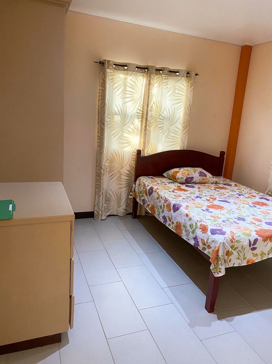 Bedroom with double bed, dresser and leafy curtains