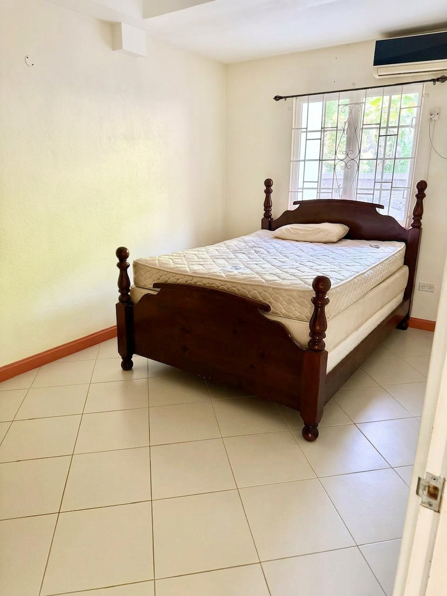Bedroom with queen bed, tiled floors and garden-facing window