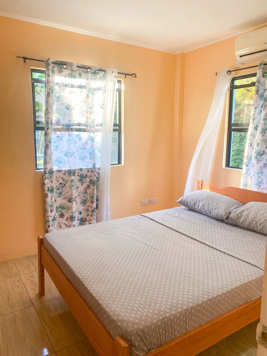 Air-conditioned bedroom with queen bed and twin windows