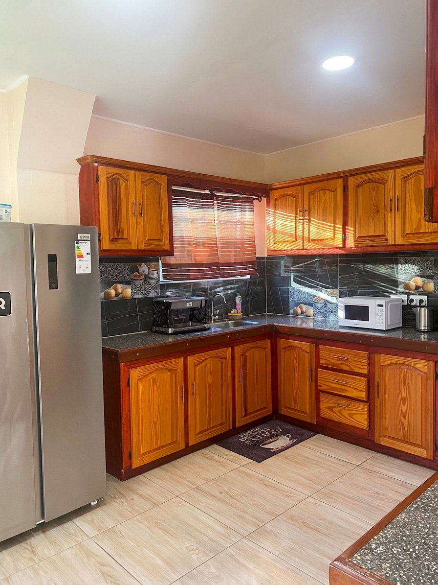 Modern kitchen with full-size stainless refrigerator and granite counters