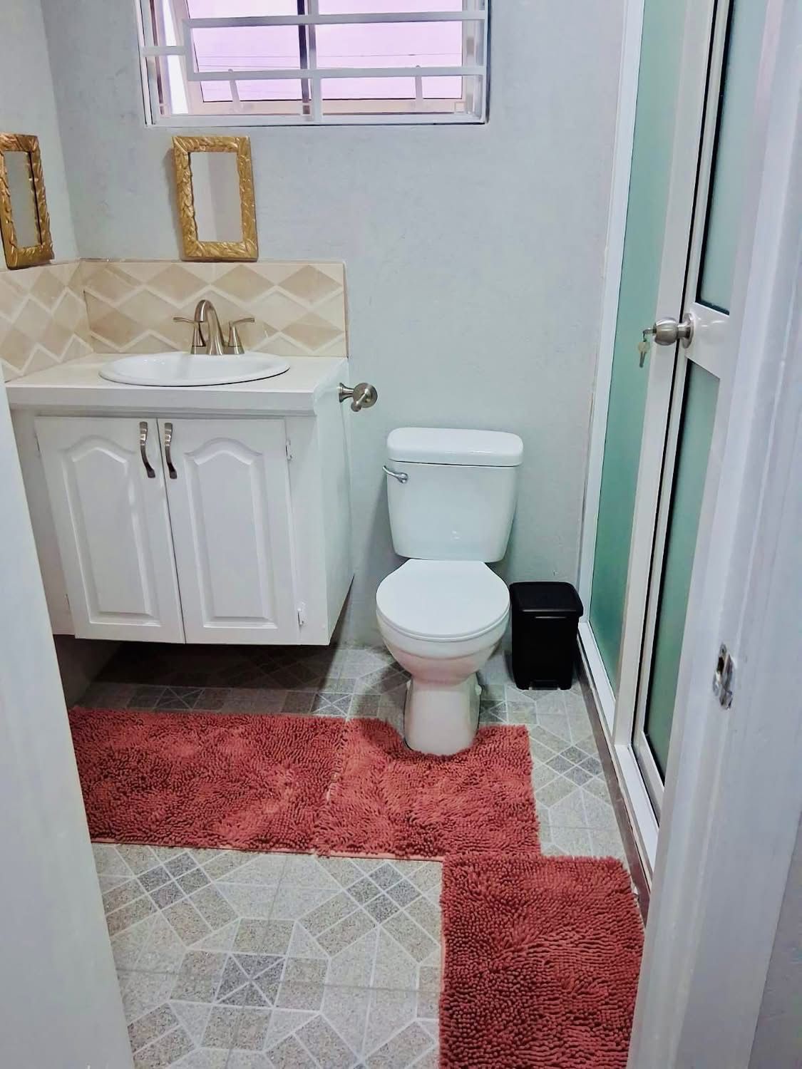 Bathroom with vanity, toilet and decorative gold-framed mirrors