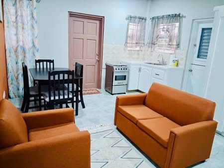 Open-plan living area with orange sofas, dining set and full kitchen