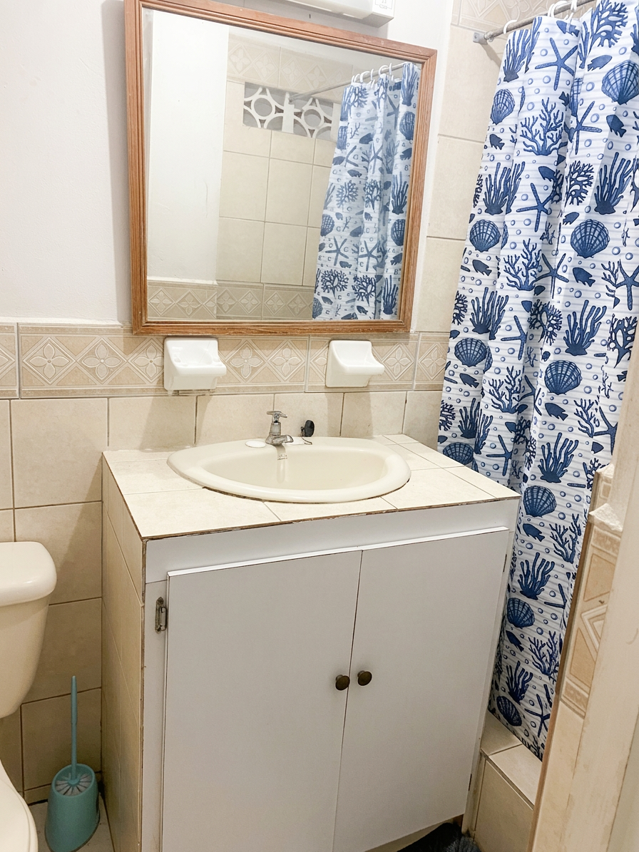 Bathroom with tiled vanity, mirror and shower curtain