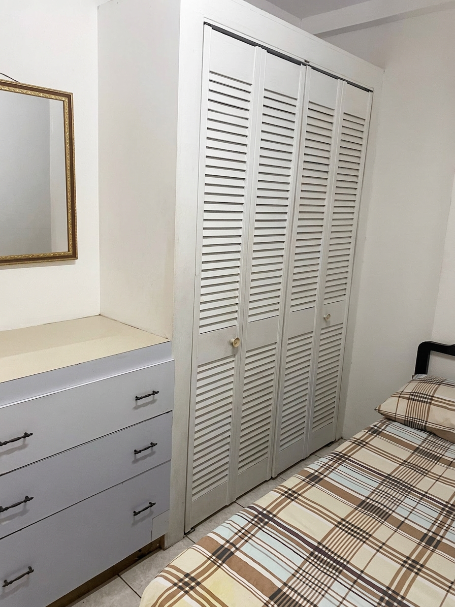 Bedroom with built-in closet, dresser and bed