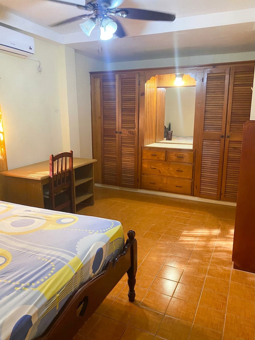 Primary bedroom view with large built-in wooden wardrobes and dresser
